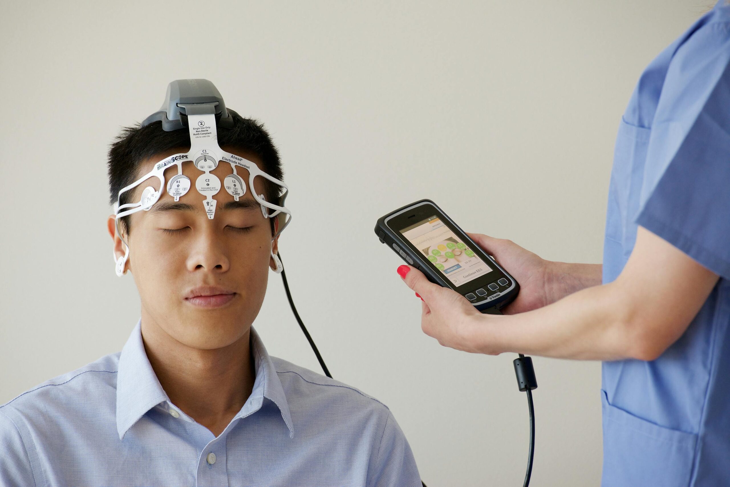 Healthcare professional conducting an EEG examination using a Brainscope device on a male patient.